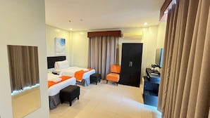 Une chambre d’hôtel avec deux lits, un bureau, une chaise, une armoire et un téléviseur.