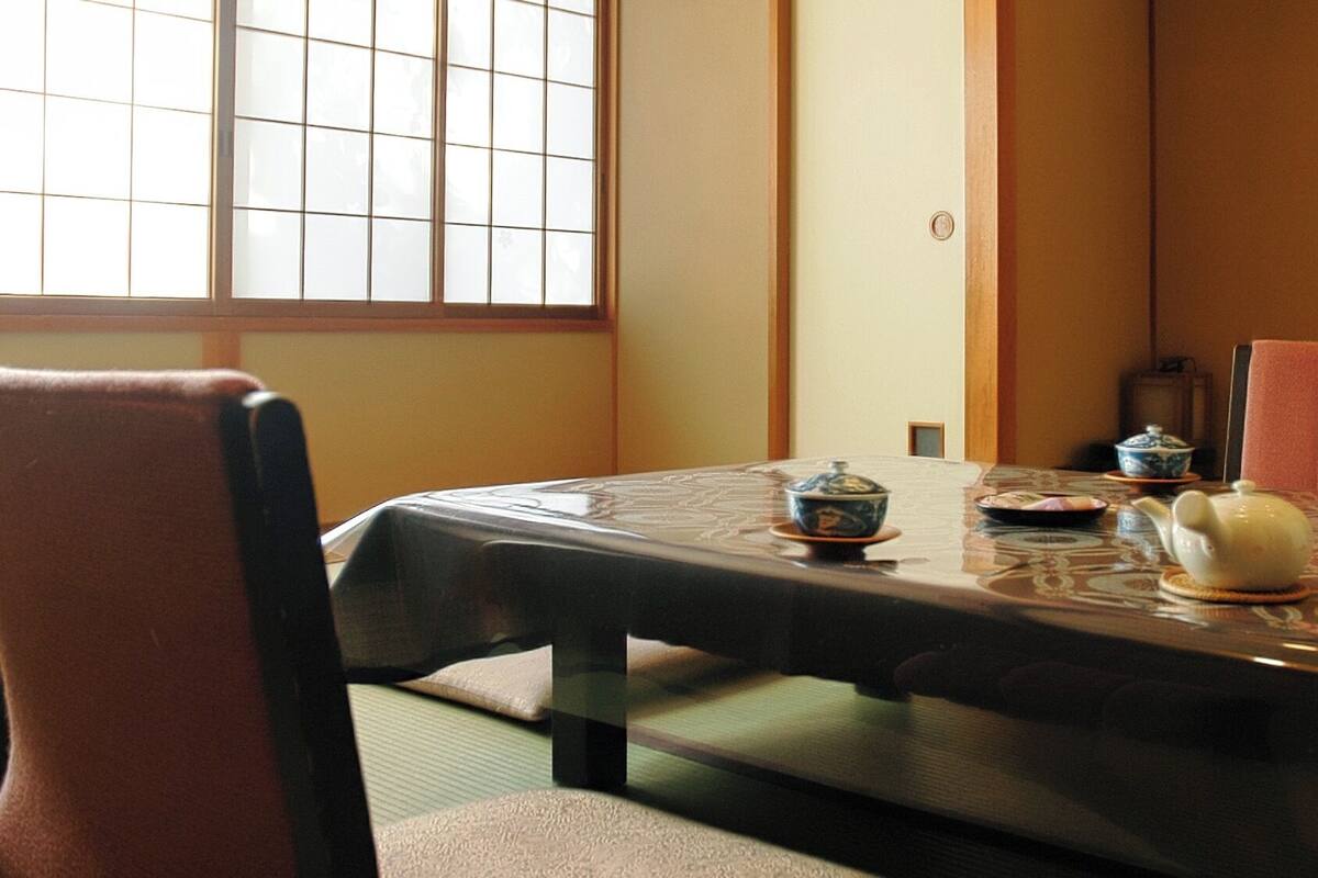 Een traditionele Japanse kamer met tatami vloerbedekking, een lage tafel met theeservies en een schuifdeur met ruitpatroon.