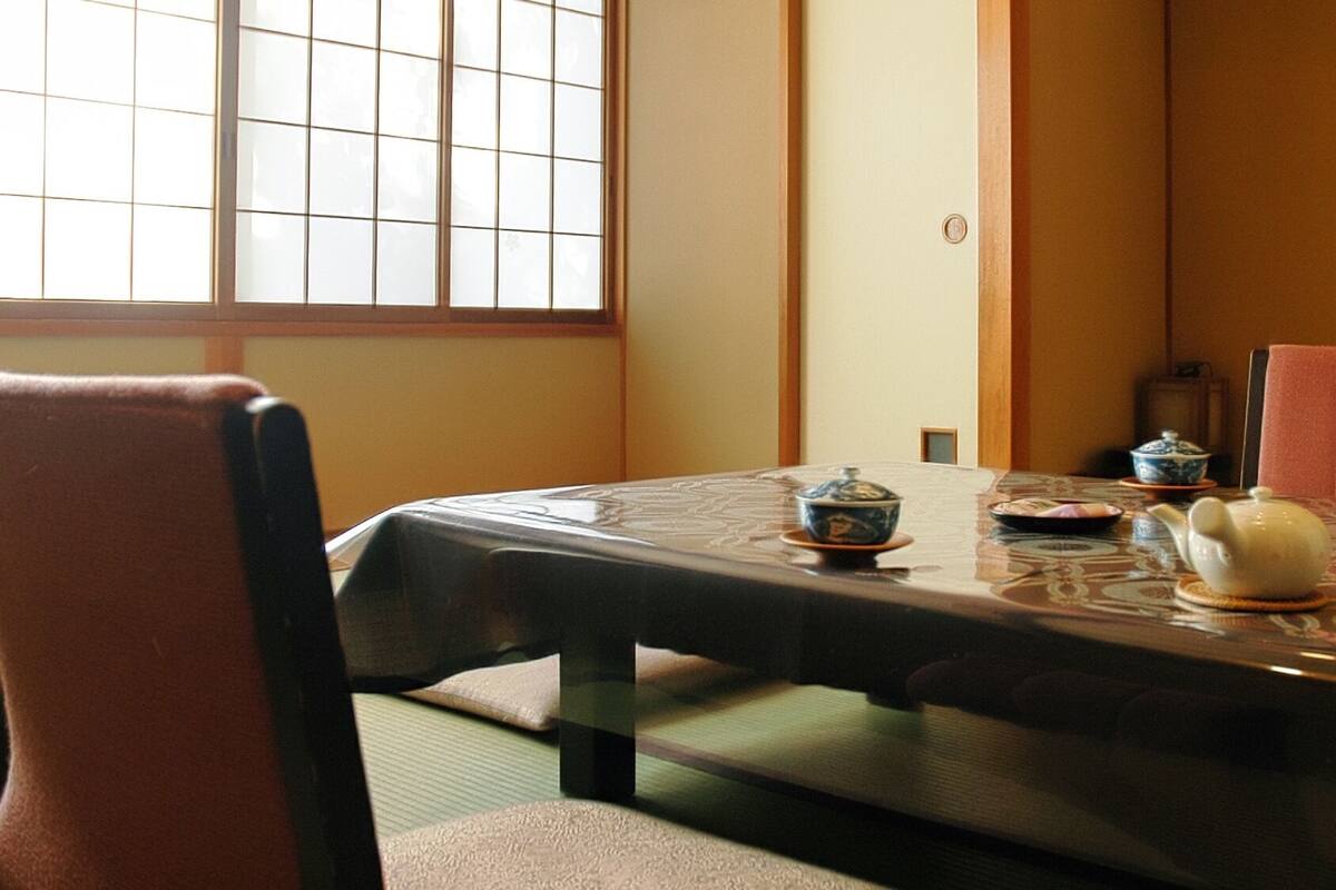 Een traditionele Japanse kamer met tatami vloerbedekking, een lage tafel met een theeset en een shoji scherm.
