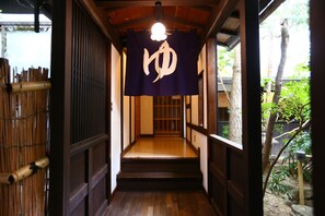 Ein traditioneller japanischer Gang mit Holzboden und einem Raum mit Tatami-Matten am Ende.