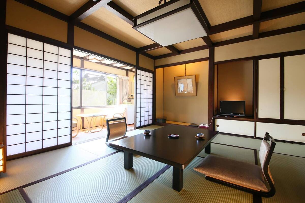 Een traditionele Japanse kamer met tatami vloerbedekking, een lage tafel en een televisietoestel.