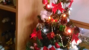 A small Christmas tree with a 'Merry Christmas' topper, surrounded by various decorations. - Pension Souvenir (Iki)