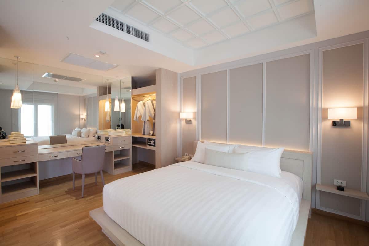 Une chambre d’hôtel moderne équipée d’un grand lit, d’un bureau, d’une chaise, d’une armoire et d’un miroir.