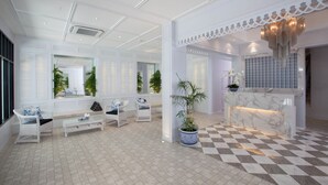 Um hall amplo com piso quadriculado, mobiliário branco e balcão de recepção.