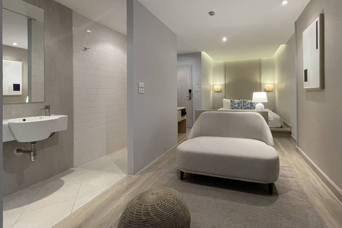 Une chambre d’hôtel moderne, dotée d’un grand miroir, d’un lavabo, d’un canapé et d’un lit.