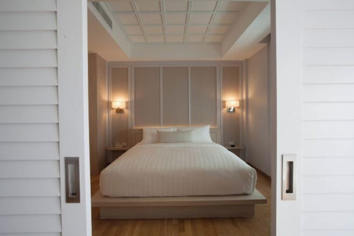 Un dormitorio con una cama grande, dos lámparas de noche y un techo con diseño de cuadrícula.