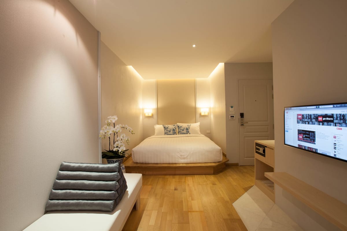 Une chambre à coucher moderne avec un lit, des tables de chevet, un banc et un téléviseur.