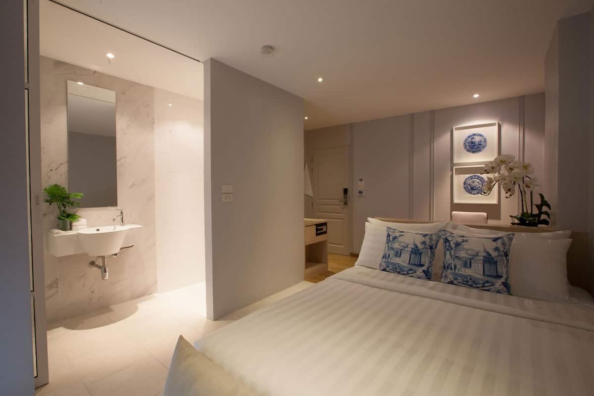 Une chambre moderne avec un grand lit, un lavabo intégré et un miroir.