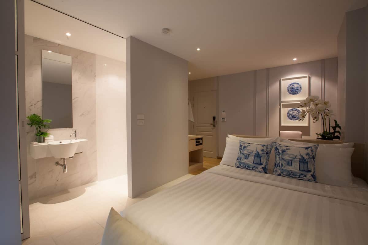 Une chambre moderne avec un grand lit, un lavabo intégré et un miroir.