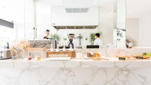 Cozinha moderna com bancadas de mármore, cafeteira e uma placa com o nome 'Kay's'.