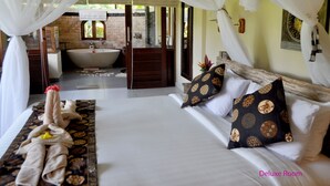 A deluxe room with a large bed, a bathroom with a bathtub, and a view of greenery. - Subak Tabola Villa (Sidemen)