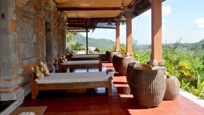 A covered outdoor seating area with benches and wicker planters, overlooking a lush landscape. - Subak Tabola Villa (Sidemen)