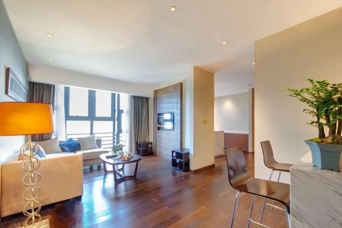 Un salon moderne avec un canapé, une table basse et des fauteuils, une cheminée et une grande fenêtre.