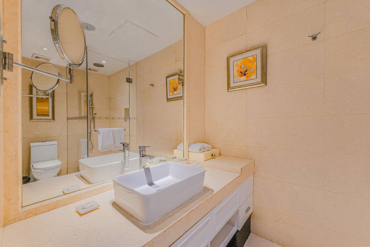 A modern bathroom with a large mirror, a white sink, and a bathtub.