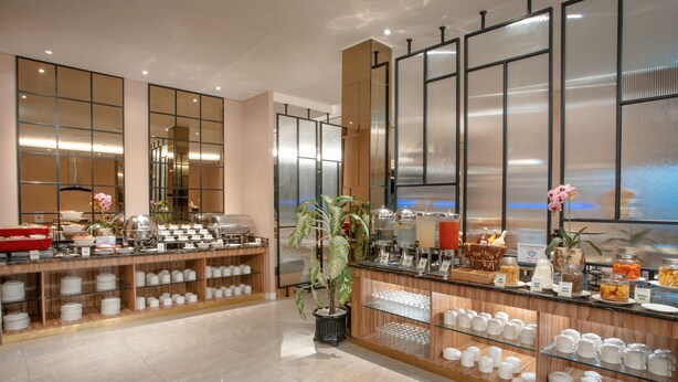 A buffet area with various food items and dishes displayed on shelves and counters. - Grand Zuri Hotel Duri (Mandau)