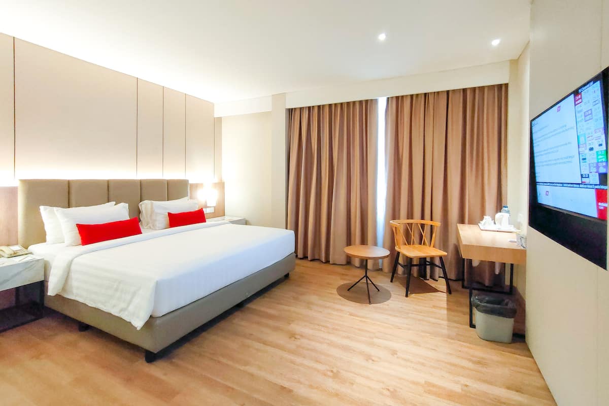 Ein Hotelzimmer mit Bett, Schreibtisch, Stuhl, Fernseher und Mülleimer.