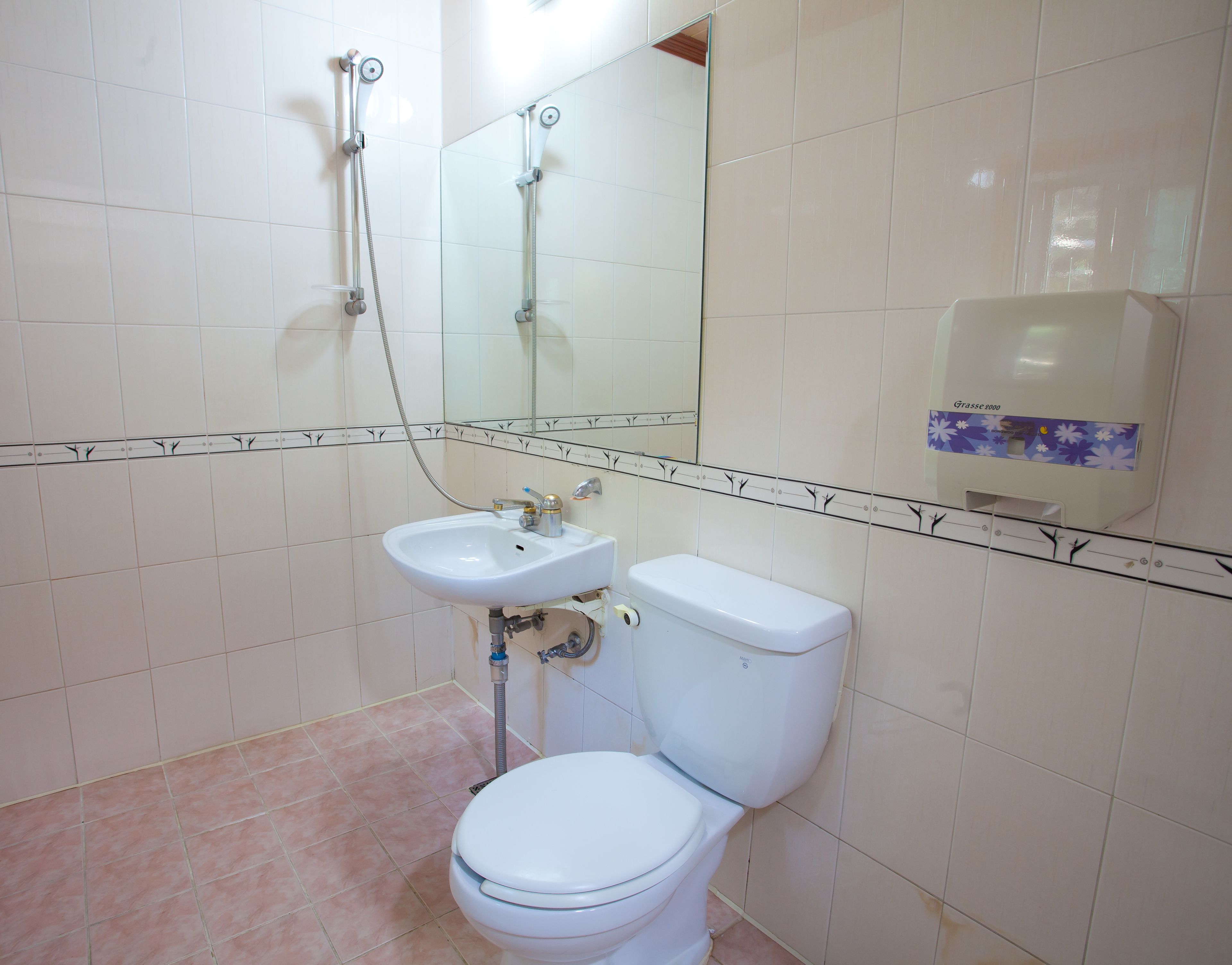 Un baño con lavamanos, inodoro y ducha blancos.
