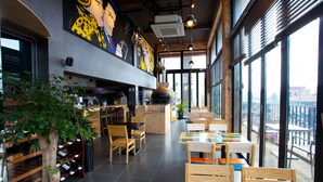 A restaurant interior with wooden tables and chairs, a large potted plant, and a mural on the wall. - White Cabin (Pyeongchang)