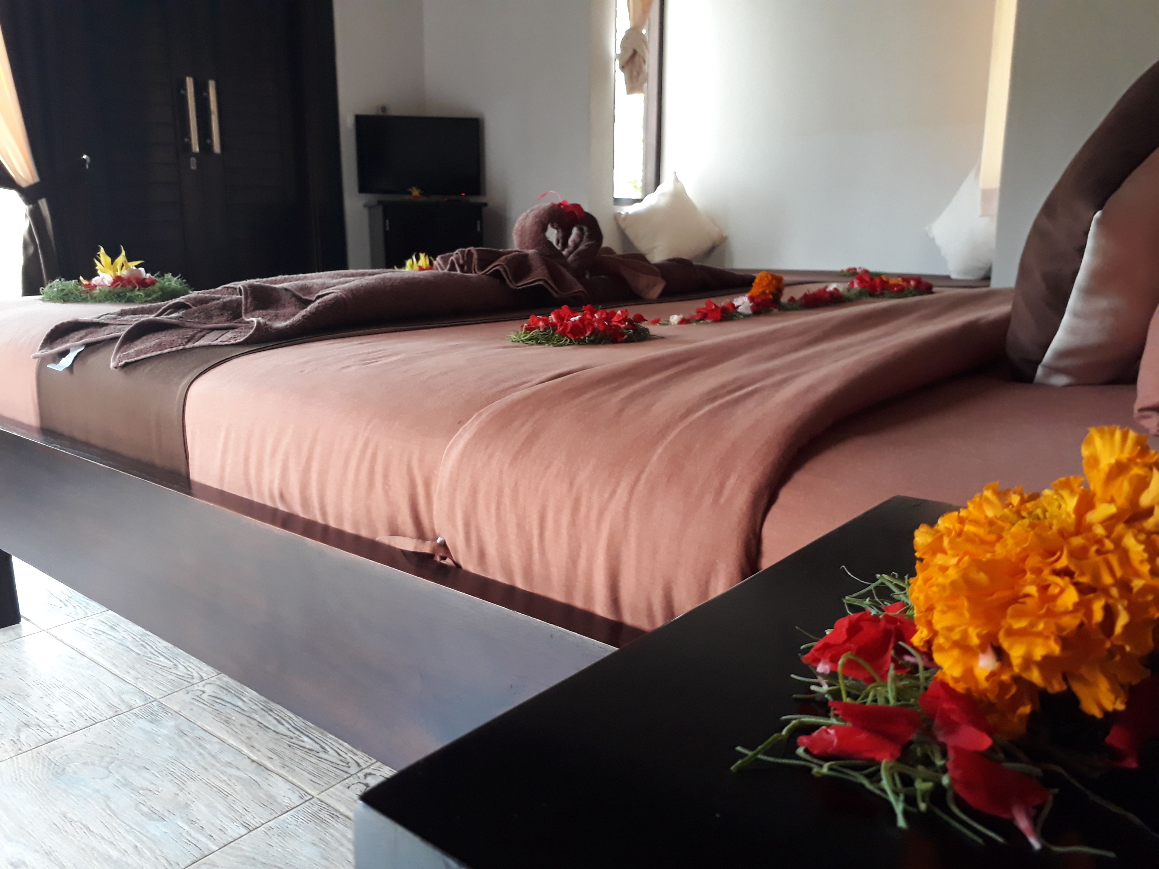 Een moderne slaapkamer met een groot bed, een flatscreen televisie en een raam met gordijnen.
