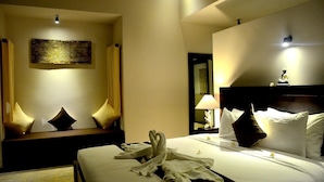 Habitación de hotel con cama, mesita de noche, lámpara, espejo y un adorno en la pared.