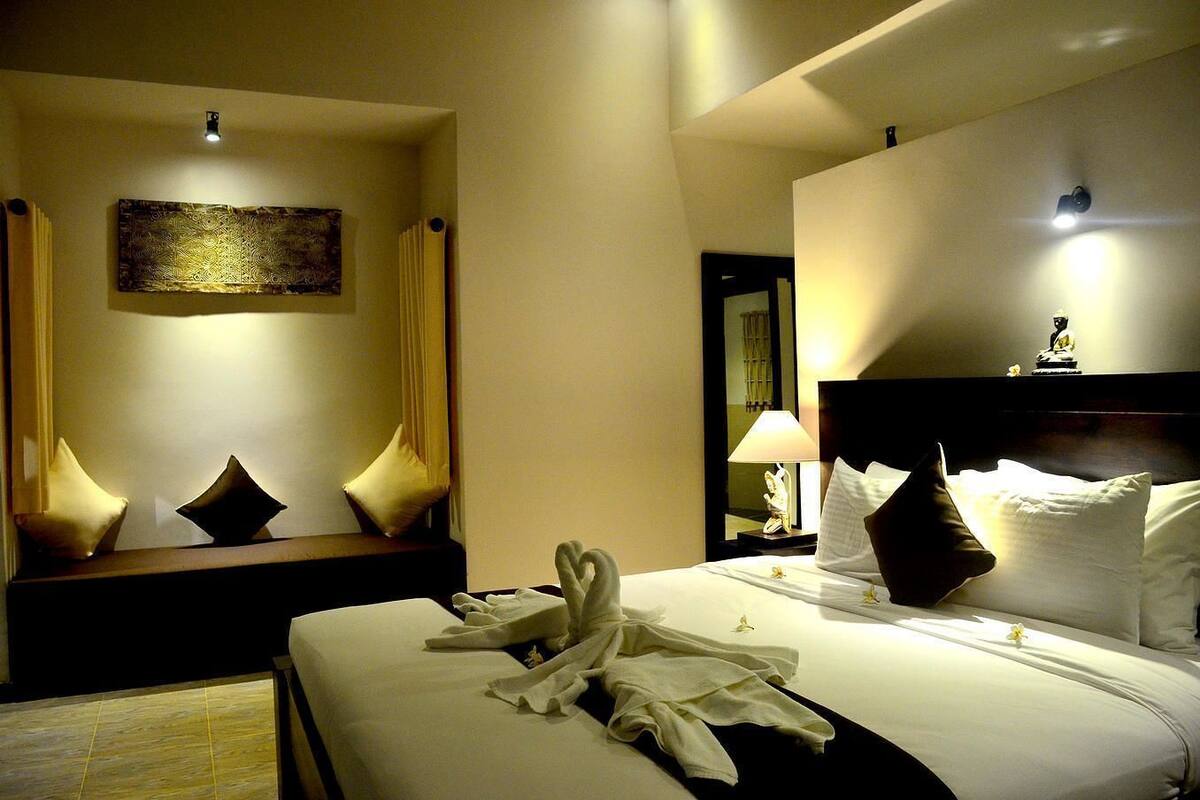 Una habitación de hotel con una cama, una mesita de noche, una lámpara, un espejo y una obra de arte en la pared.