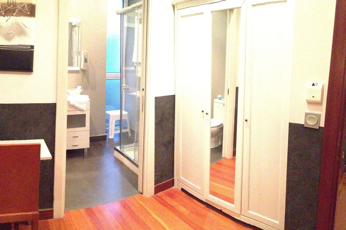 A bedroom with a bed, bedside table, chair, and a small desk.