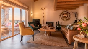 A spacious living room with a large window, wooden ceiling beams, a stone pillar, and a variety of seating options. - Monte do Cardal (Aljezur)