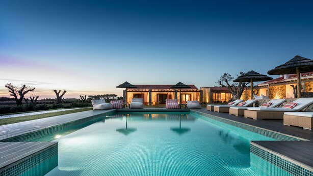 A swimming pool with lounge chairs and umbrellas, surrounded by a building with a tiled roof. - Monte do Cardal (Aljezur)