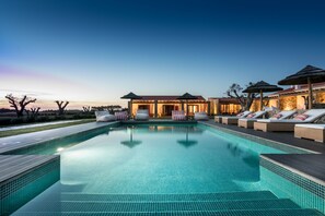 A swimming pool with lounge chairs and umbrellas, surrounded by a building with a tiled roof. - Monte do Cardal (Aljezur)