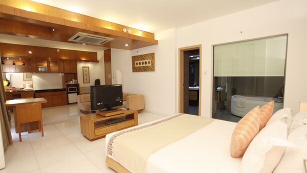 A hotel room with a bed, a television, a desk, and a kitchenette in the background. - Platinum Suites (Dhaka)