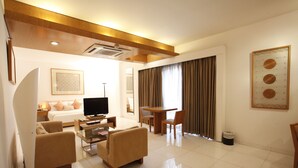 A modern hotel room with a living area, a television, a dining table, and a large window with curtains. - Platinum Suites (Dhaka)