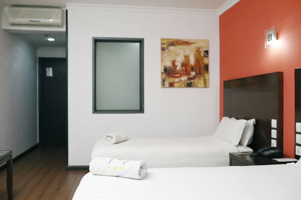 Une chambre d’hôtel avec un lit, une table de chevet, un téléphone et un tableau au mur.