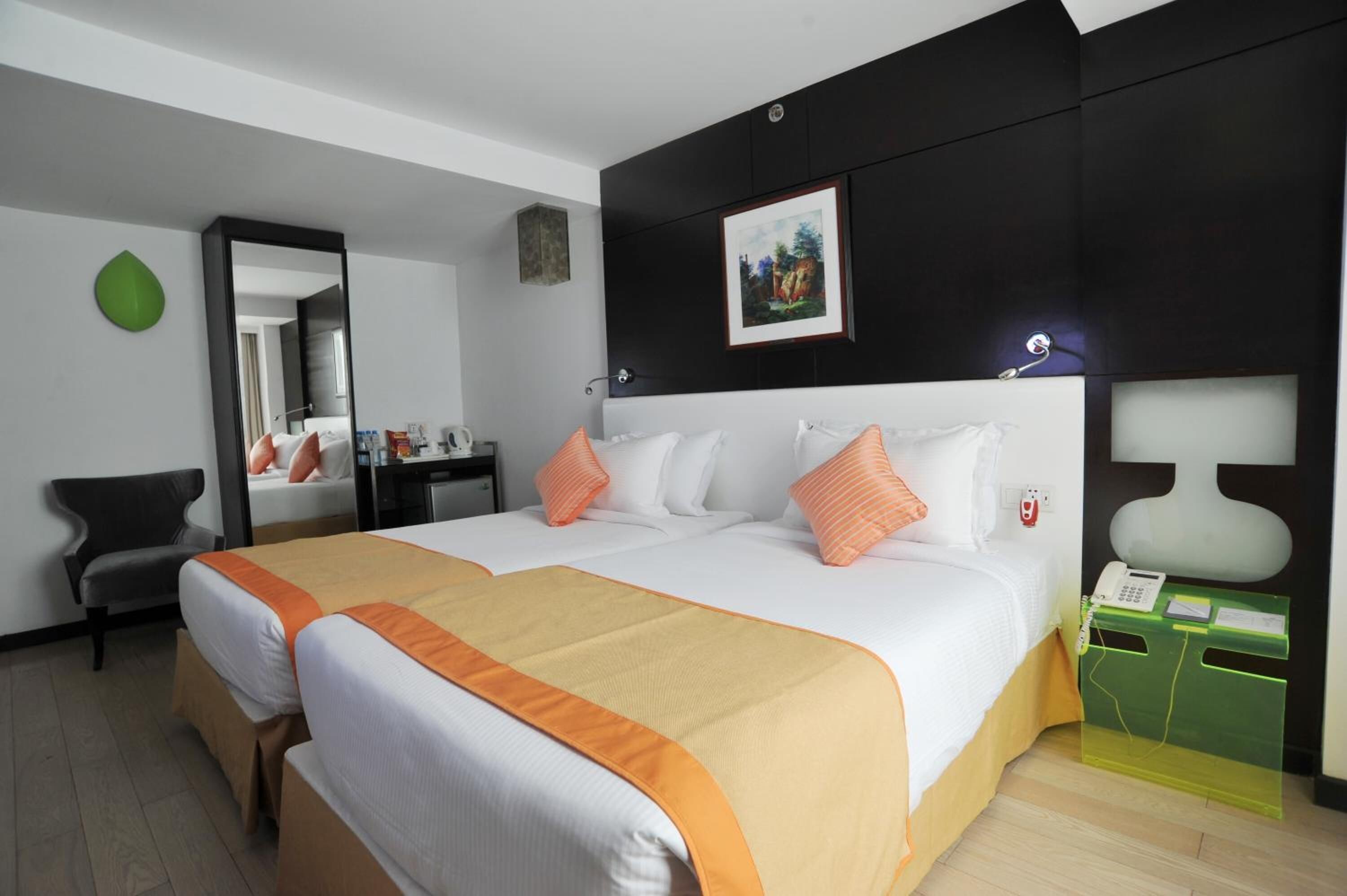 Habitación de hotel con una cama grande, dos mesitas de noche, un espejo, un escritorio y un armario verde.