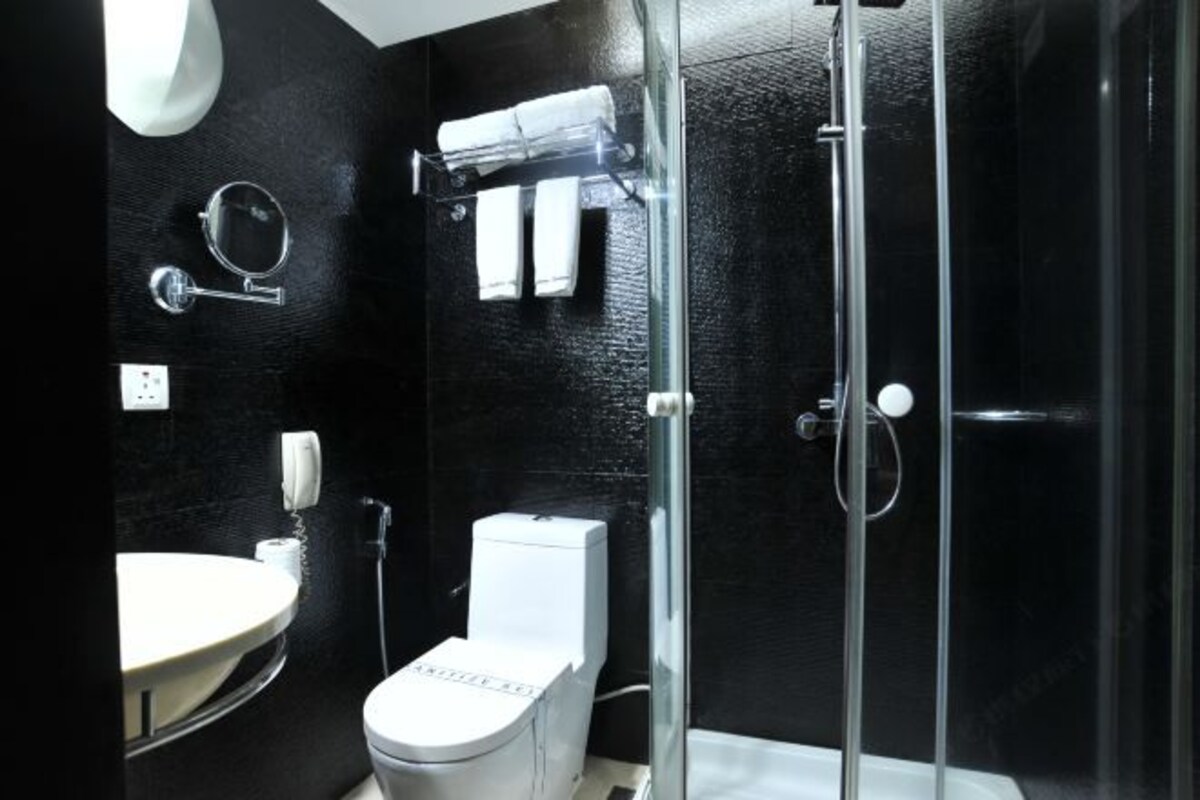 Un baño moderno con inodoro, lavamanos y ducha envuelta en vidrio.