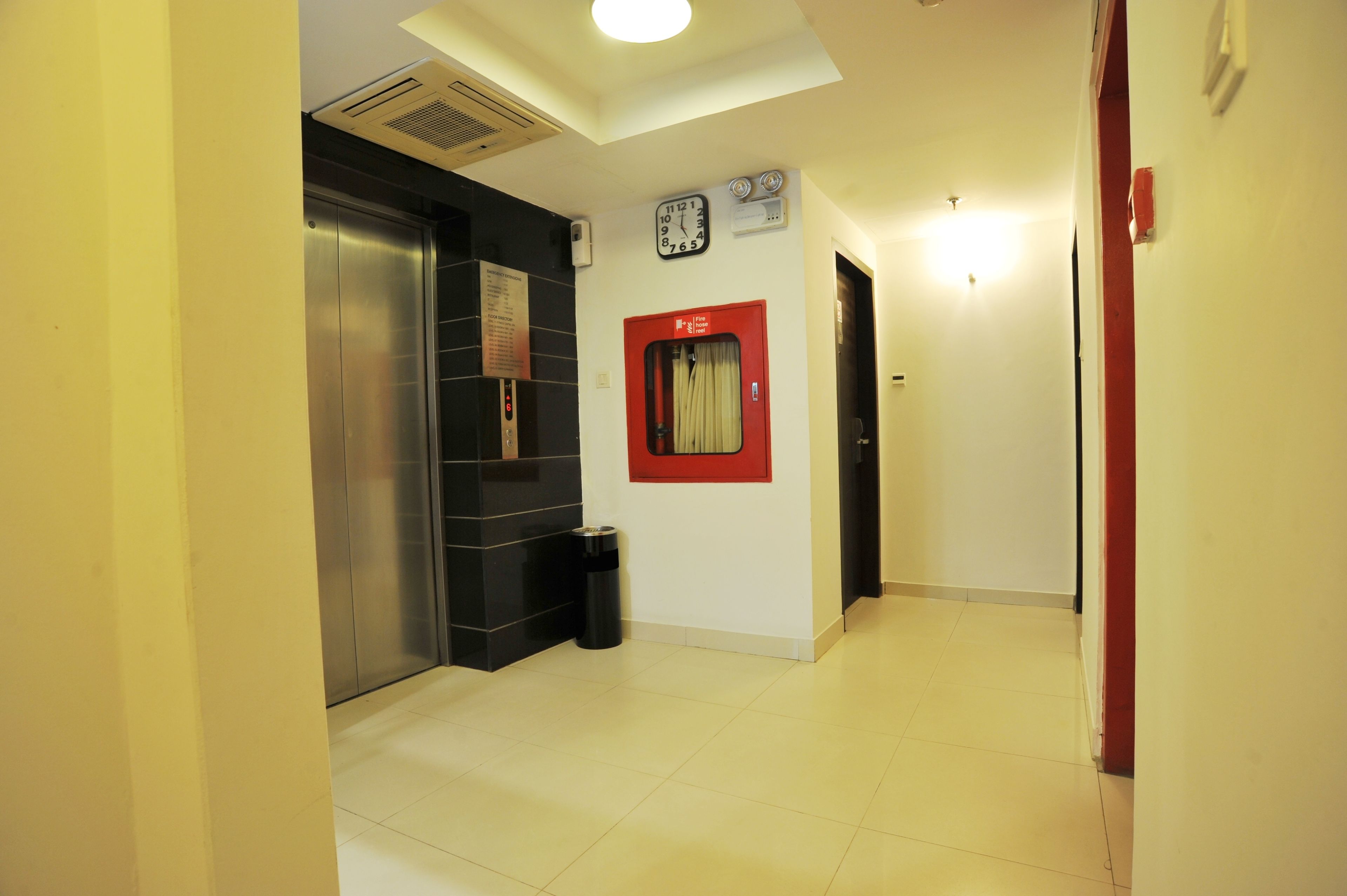 A hallway with a red-framed door, a clock, and an elevator.