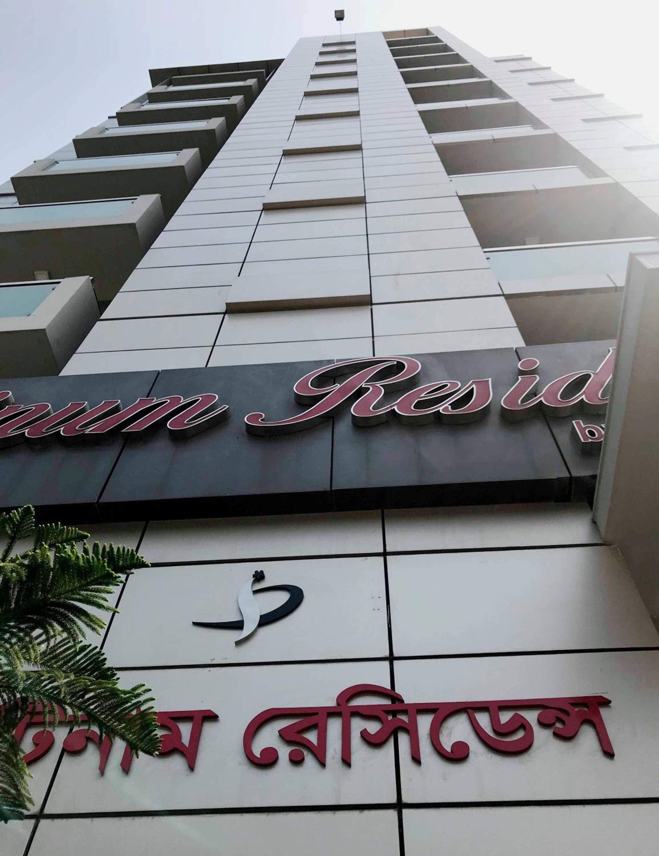 Un edificio con un letrero que dice "Resid" y otro letrero con texto en un alfabeto no latino.