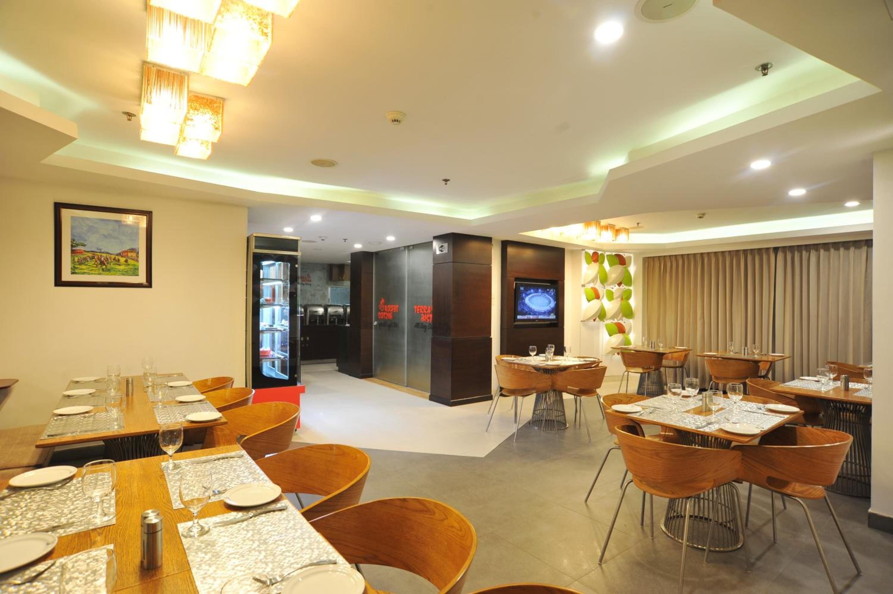 A modern dining area with tables set for guests, a television screen, and a view of the restaurant's interior.