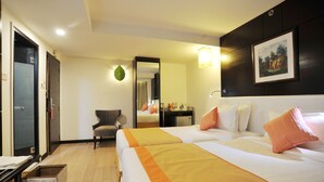 A hotel room with two beds, a desk, a chair, a mirror, and a framed picture on the wall.