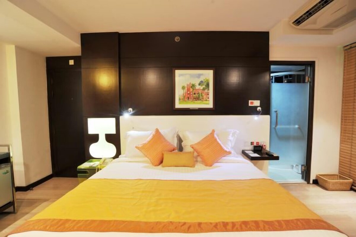 A hotel room with a large bed, a bedside table, a lamp, and a framed picture on the wall.