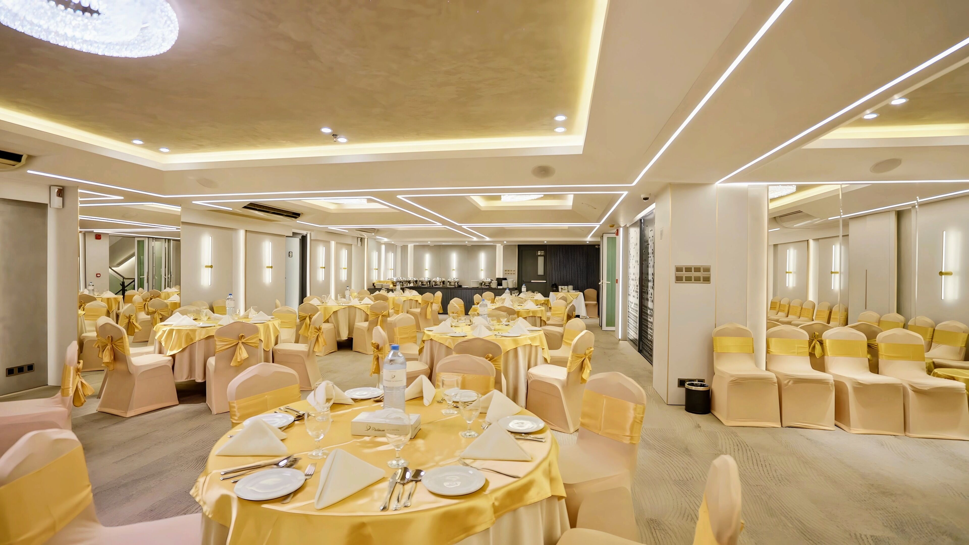 Un salón de banquetes con mesas redondas, sillas y un área de escenario.