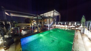 A pool area with a glass enclosure, seating, and a fan. - Platinum Grand (Dhaka)