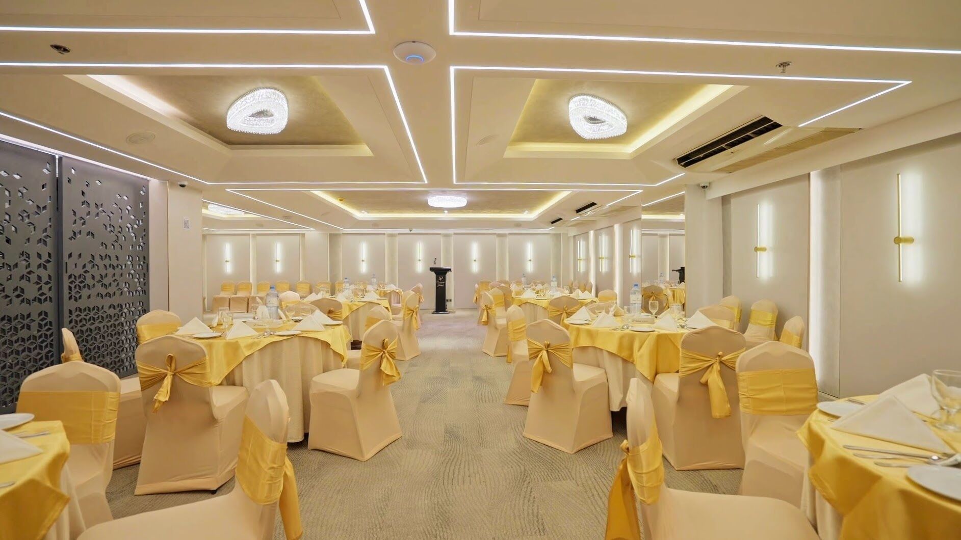 A banquet hall with round tables, chairs, and a podium.