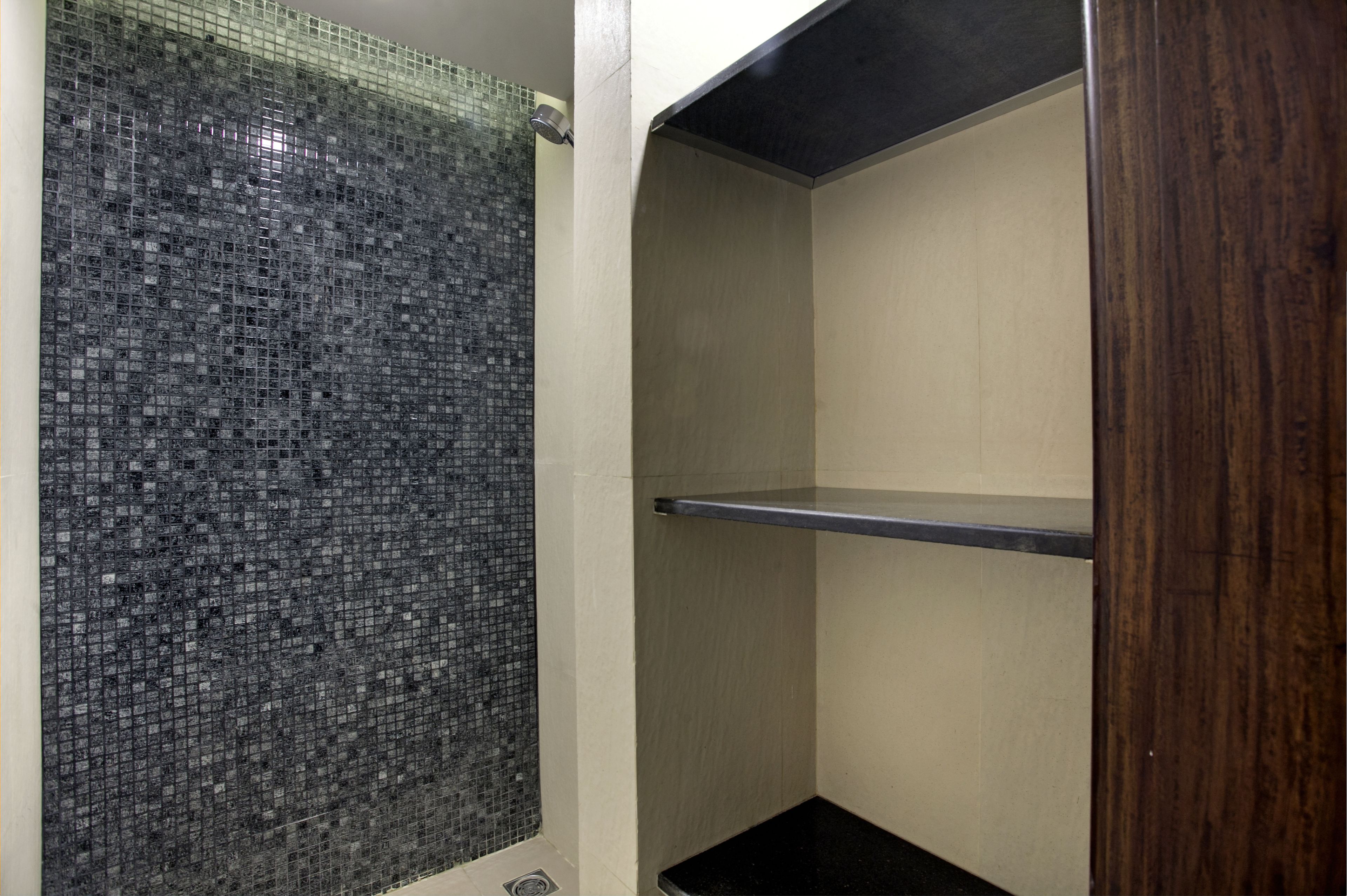 A bathroom with a tiled wall, a wooden door, and a black countertop.