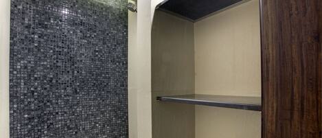 A bathroom with a tiled wall, a wooden door, and a black countertop.