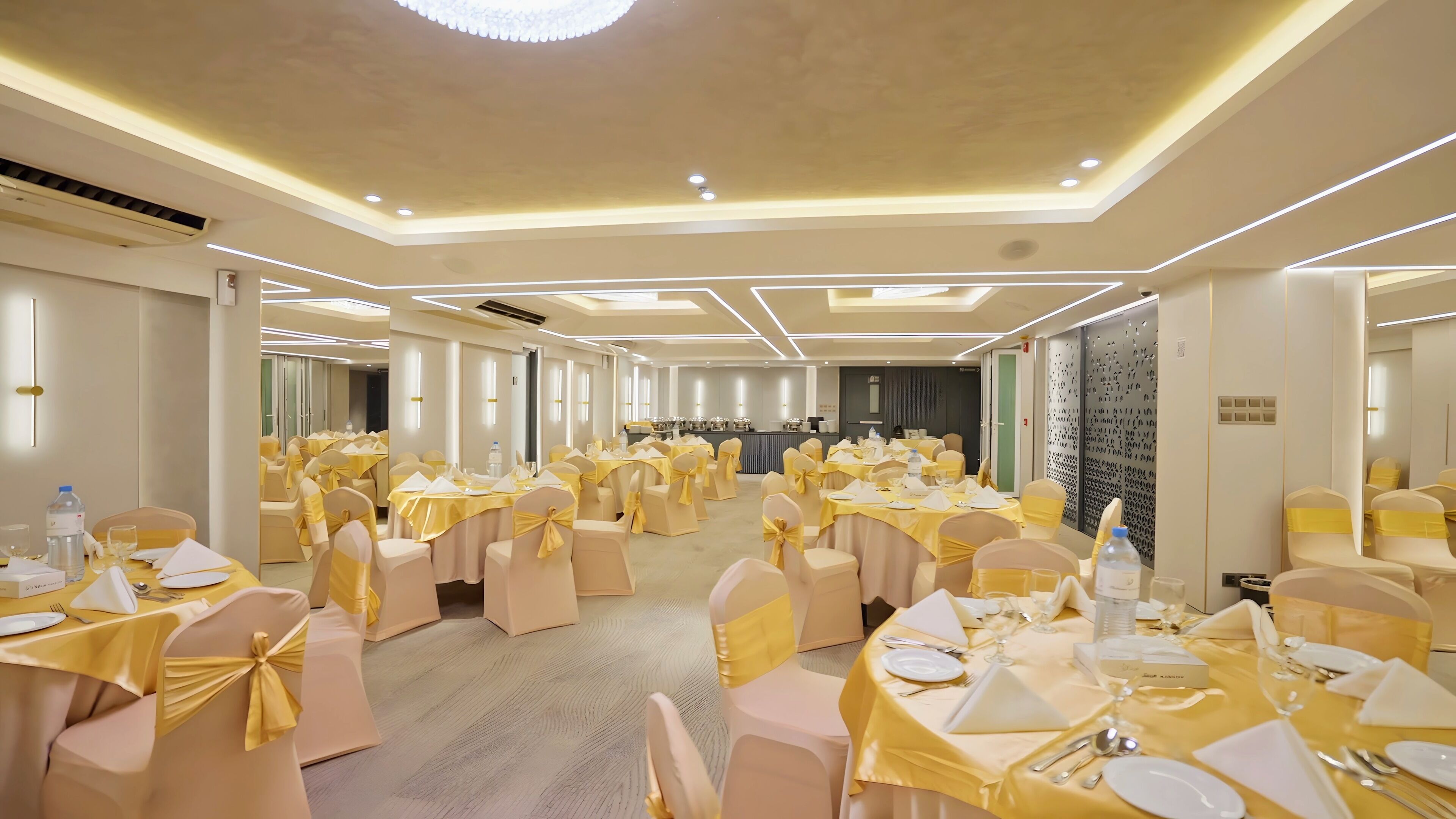 A banquet hall with round tables, chairs, and a stage area.