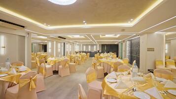 A banquet hall with round tables, chairs, and a stage area.