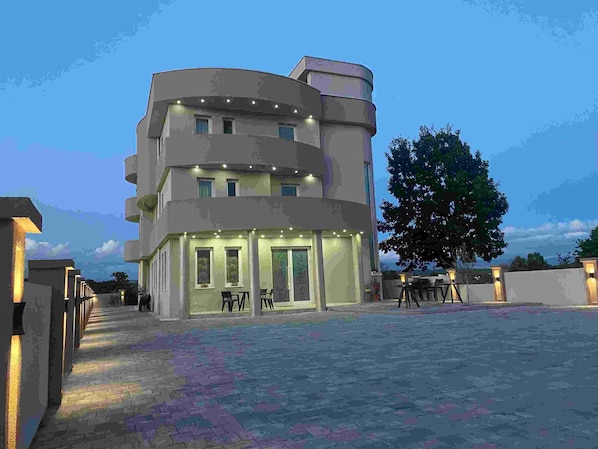 A multi-story building with a ground-level restaurant featuring outdoor seating.