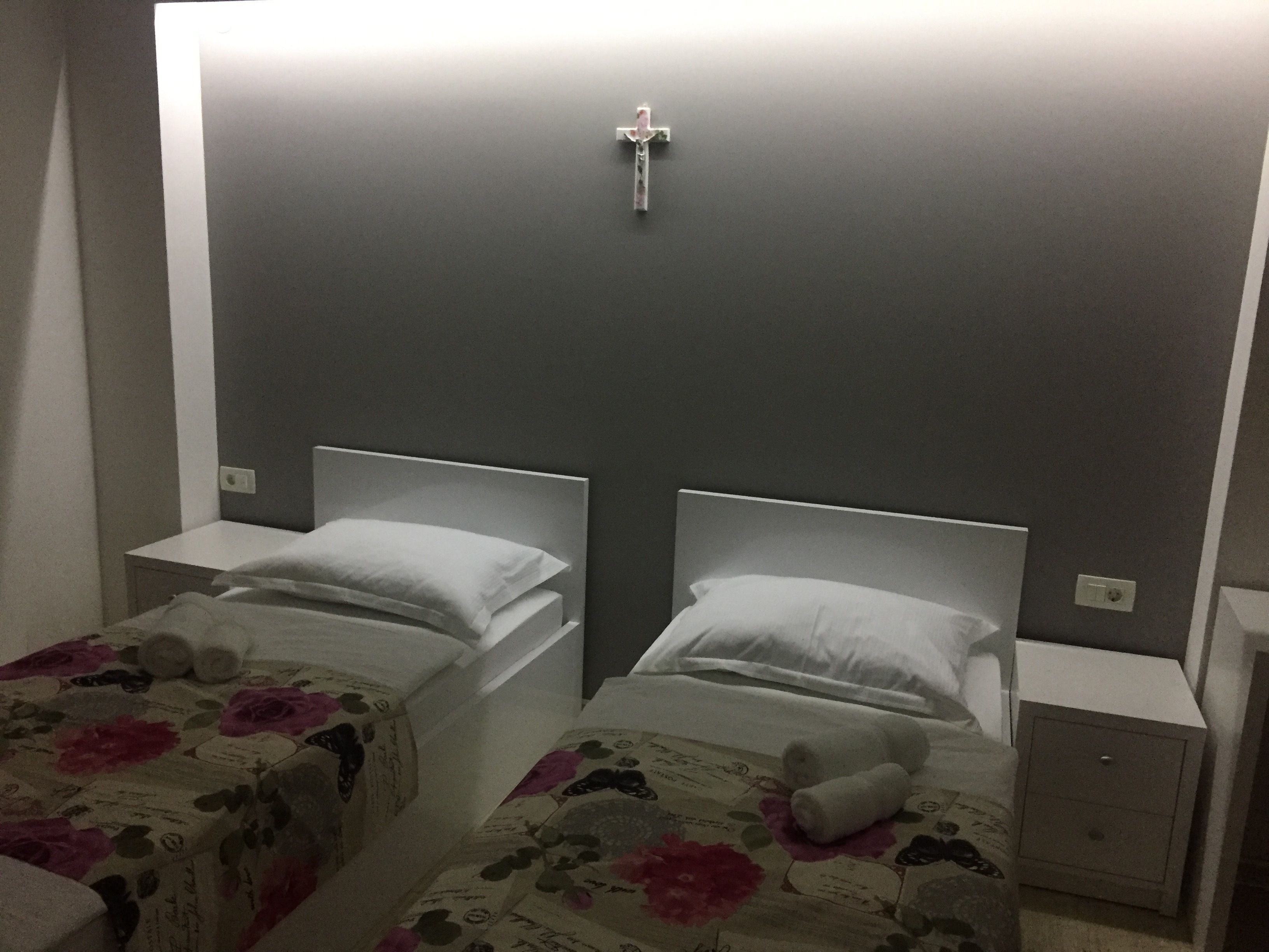 A hotel room with two beds, each with a headboard and a nightstand.