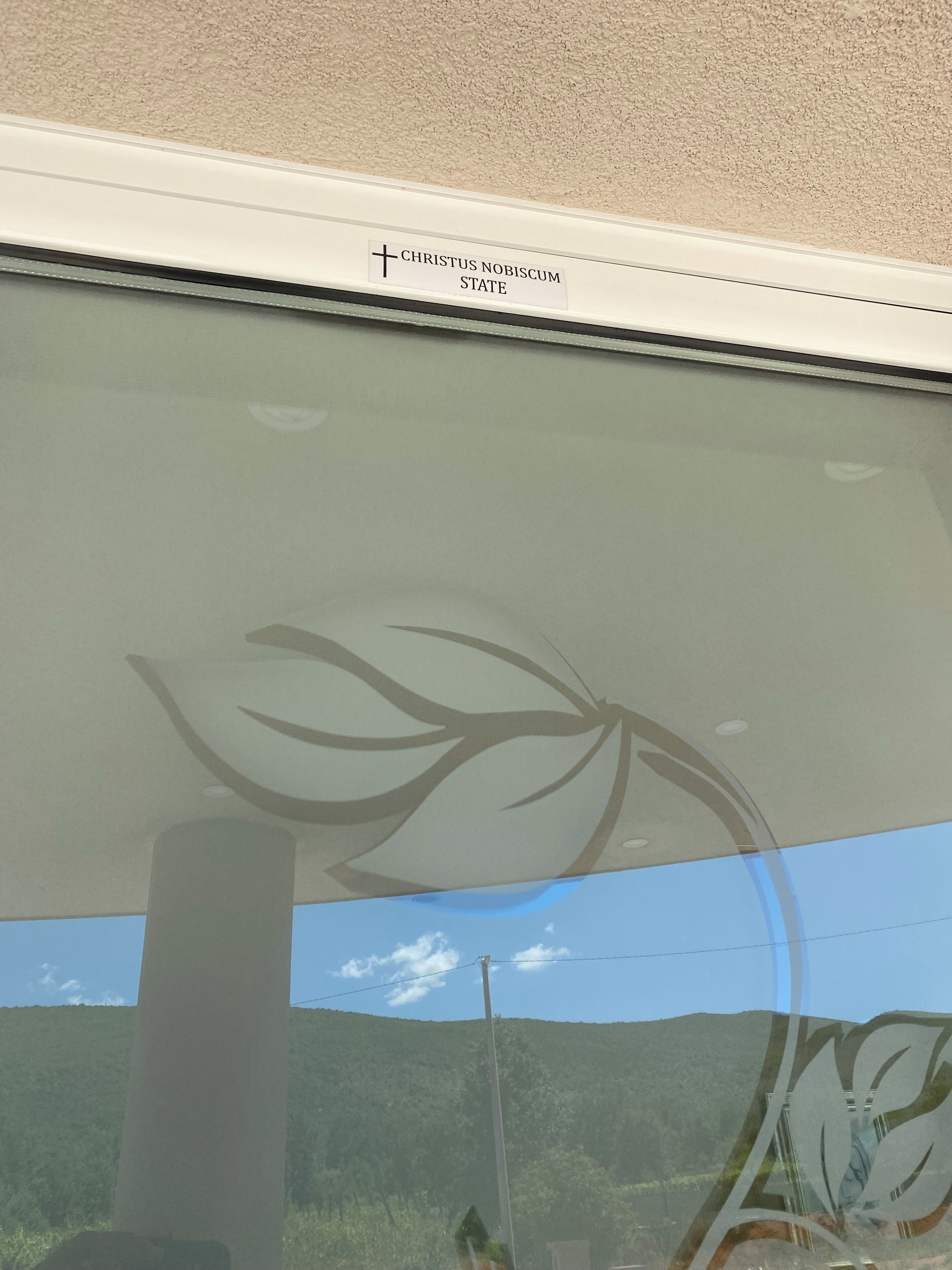 A window with a cross and the words "CHRISTUS NOBISCUM STATE" on it.