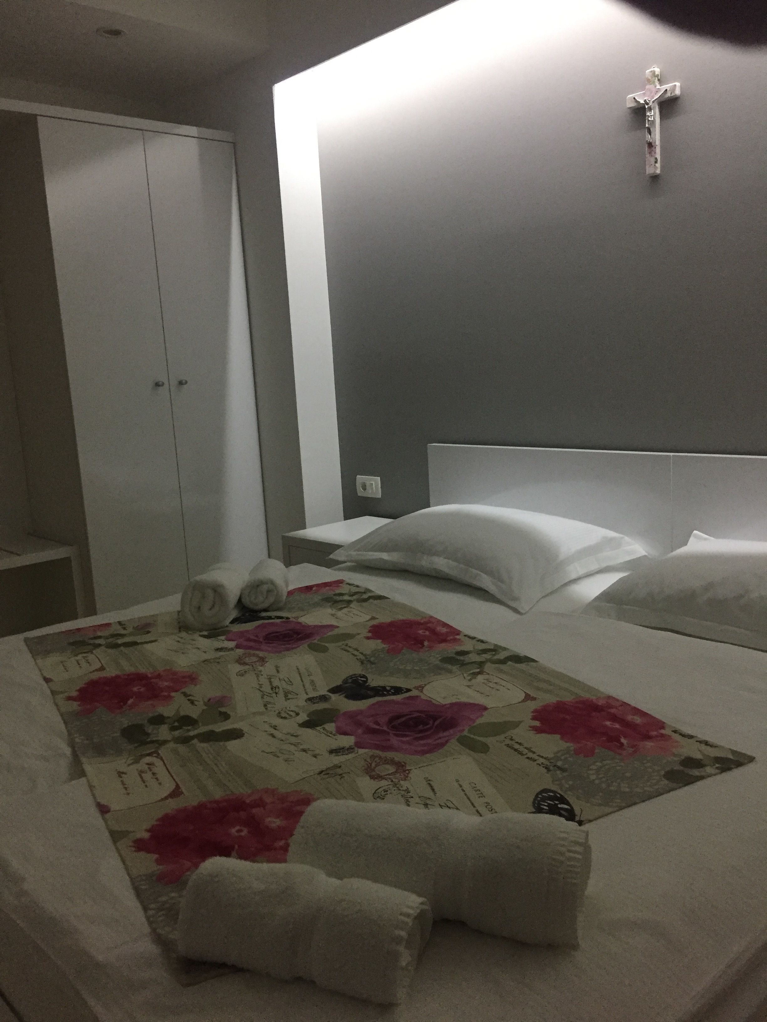Una habitación de hotel con cama, almohadas, una cruz en la pared y un armario.